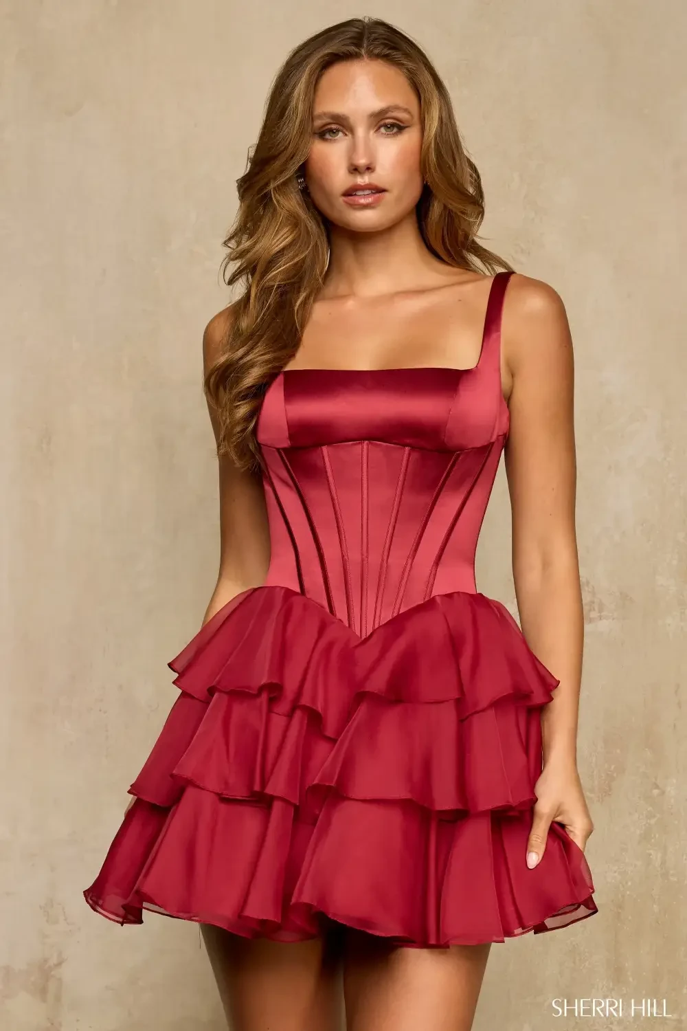 A woman wearing a red, ruffled dress with a fitted bodice and square neckline.